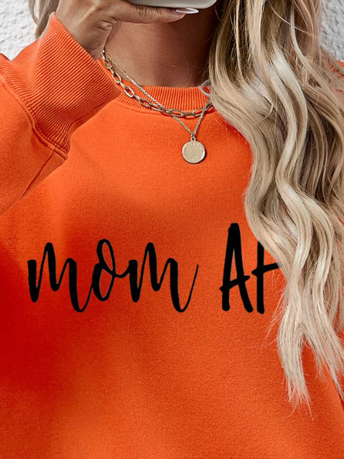 Orange graphic sweatshirt with black text that says Mom At