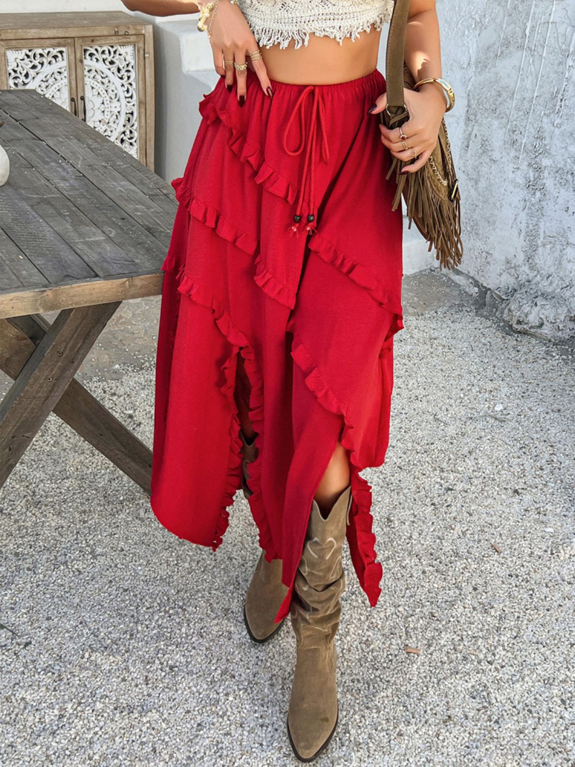 Scarlet midi skirt with cascading ruffles and a slit, styled with boots.