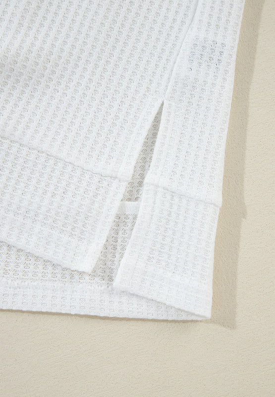 White waffle knit polo shirt with side slits and cuffed sleeves.