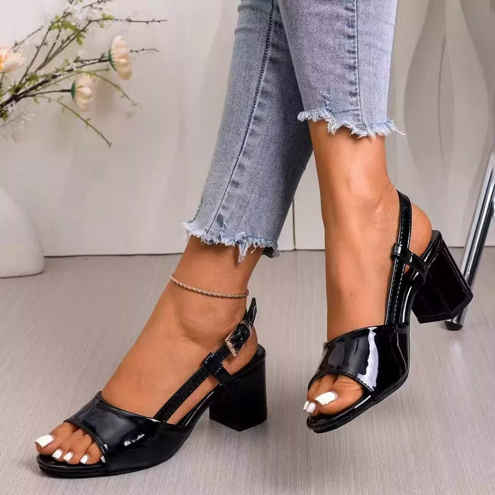 Black patent open-toe block heel sandals with ankle strap and buckle.