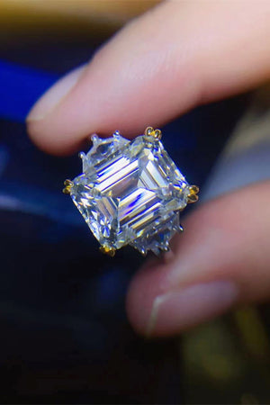 Emerald cut trilogy ring in silver with gold accents and a large center stone.