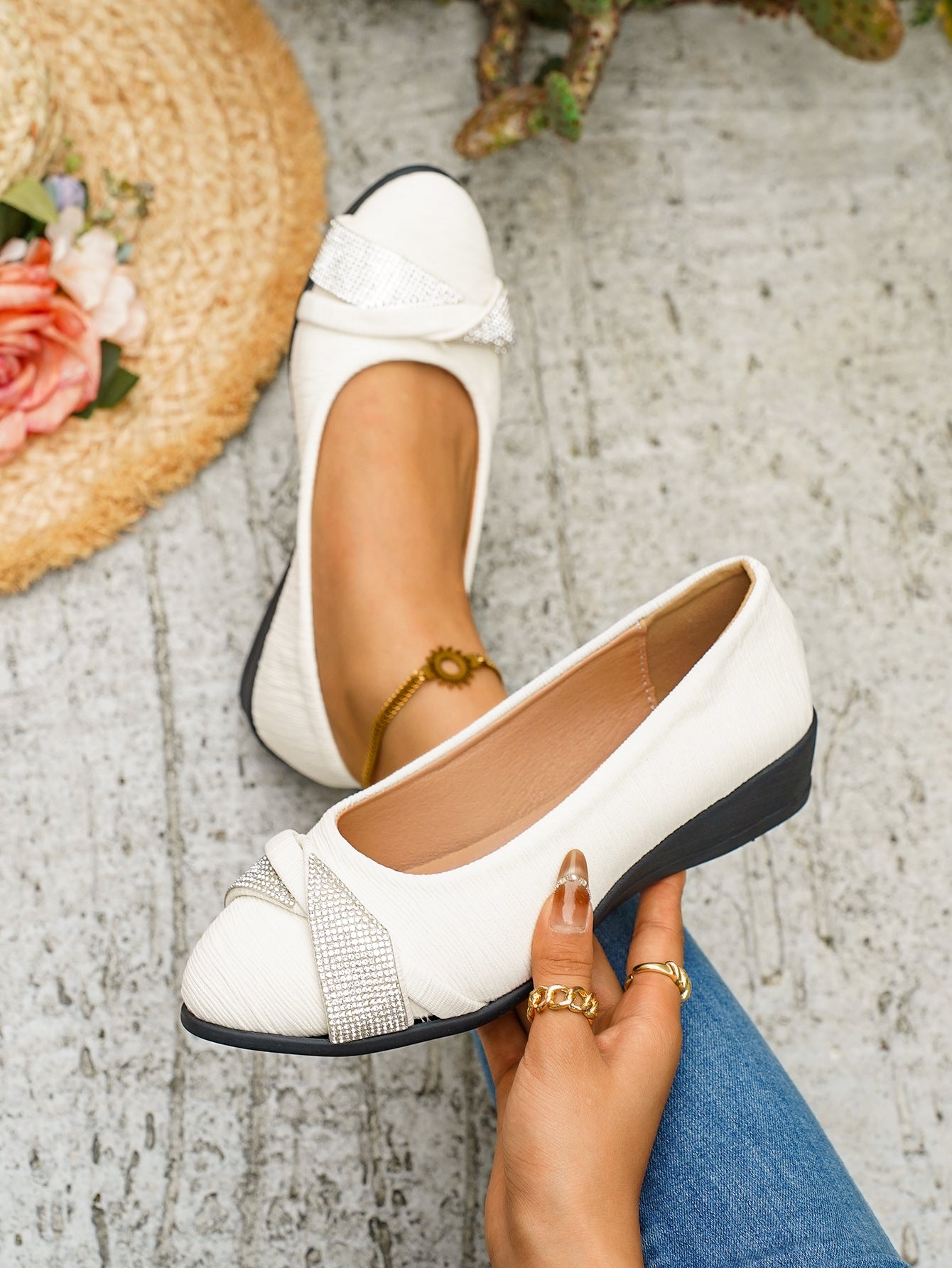 White slip-on wedge flats with rhinestone bow detail.