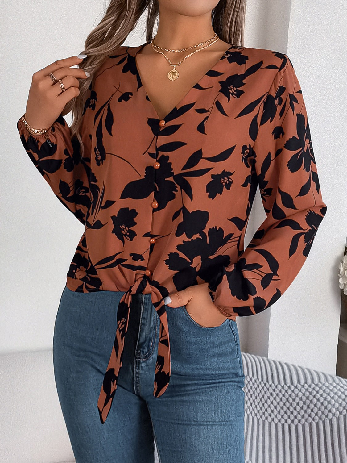Brown floral knot-front blouse with V-neck and button detail.