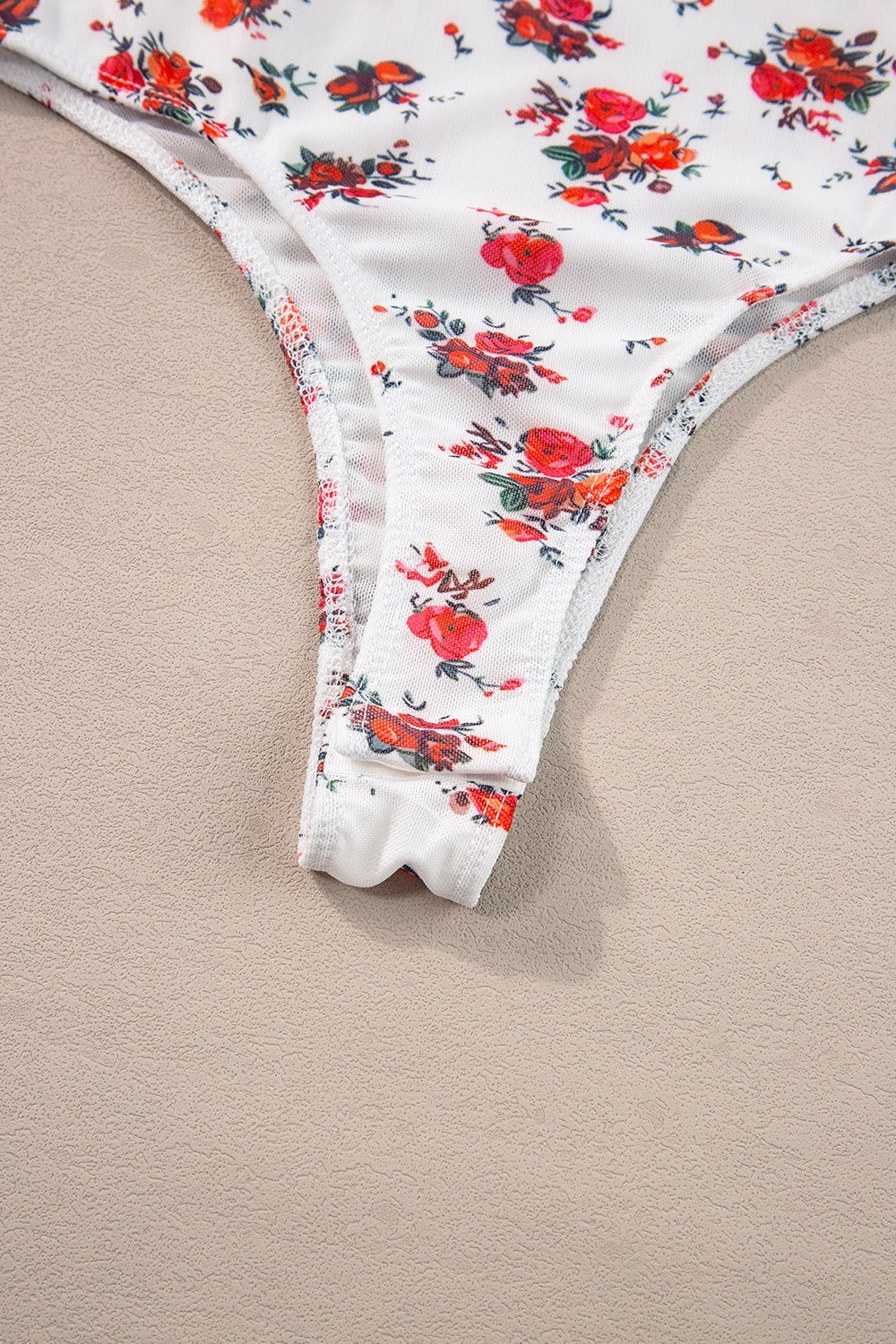 White floral bustier camisole with ruffle trim and thong bottom detail.