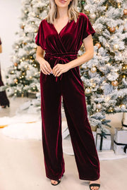 Burgundy velvet wrap bodice jumpsuit with tie waist and wide legs.