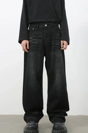 Faded black baggy denim trousers with a relaxed fit and visible distressing.