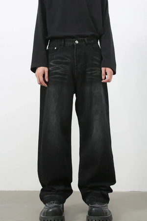 Faded black baggy denim trousers with a relaxed fit and visible distressing.