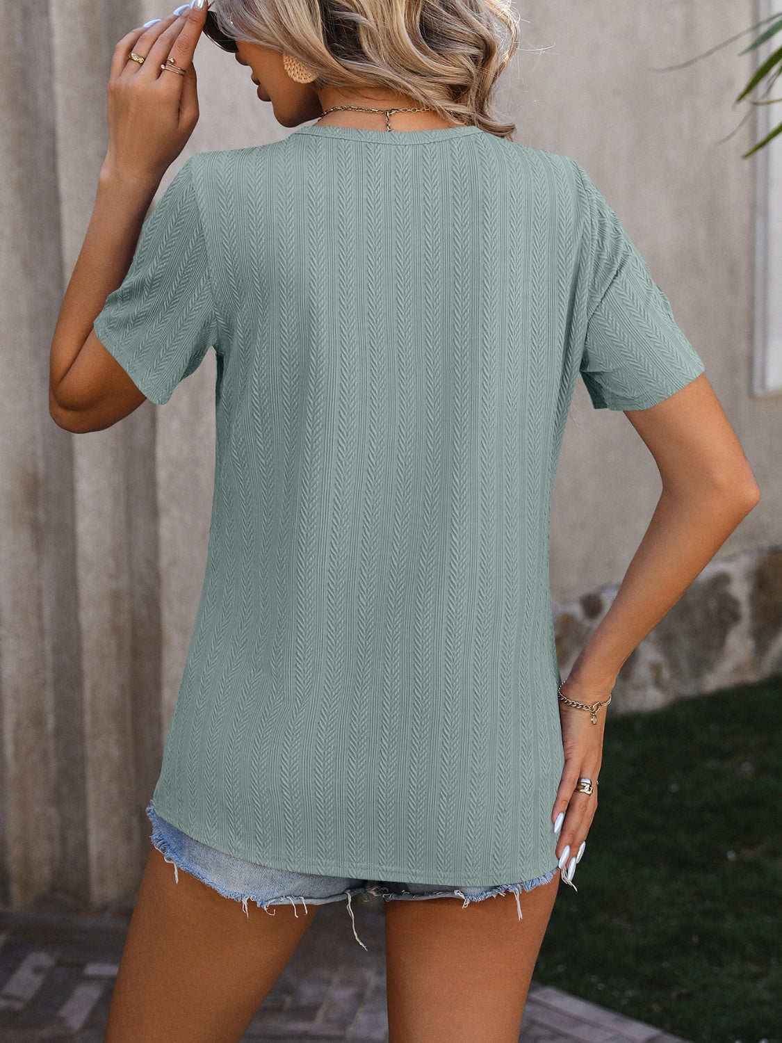 Sage green textured tee with short sleeves and split hem detail.