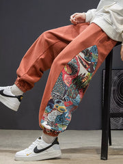 Men's orange joggers with a bold side panel print and elastic cuffs.