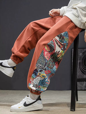 Men's orange joggers with a bold side panel print and elastic cuffs.