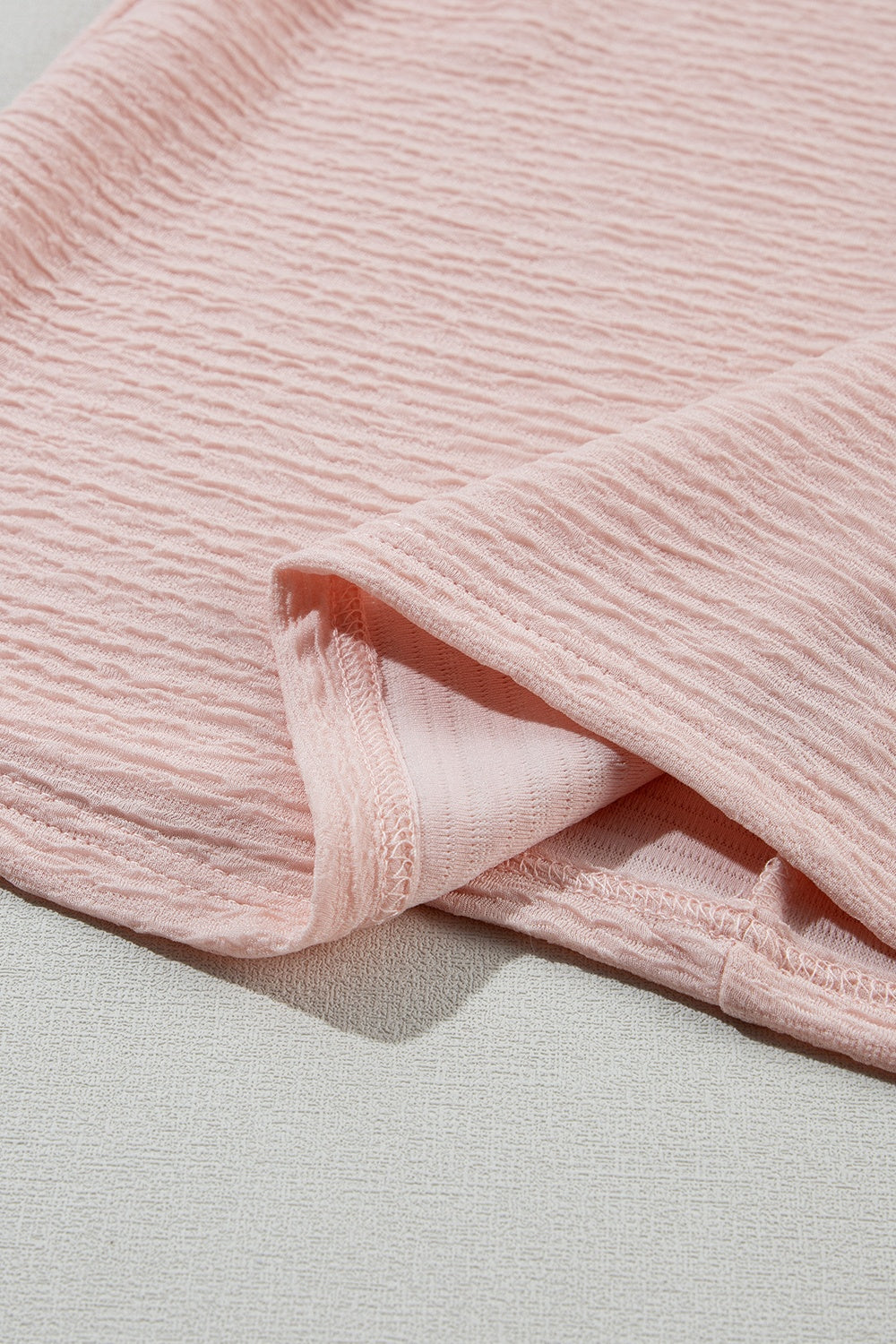 Blush pink textured blouse with ruffle sleeve detail.
