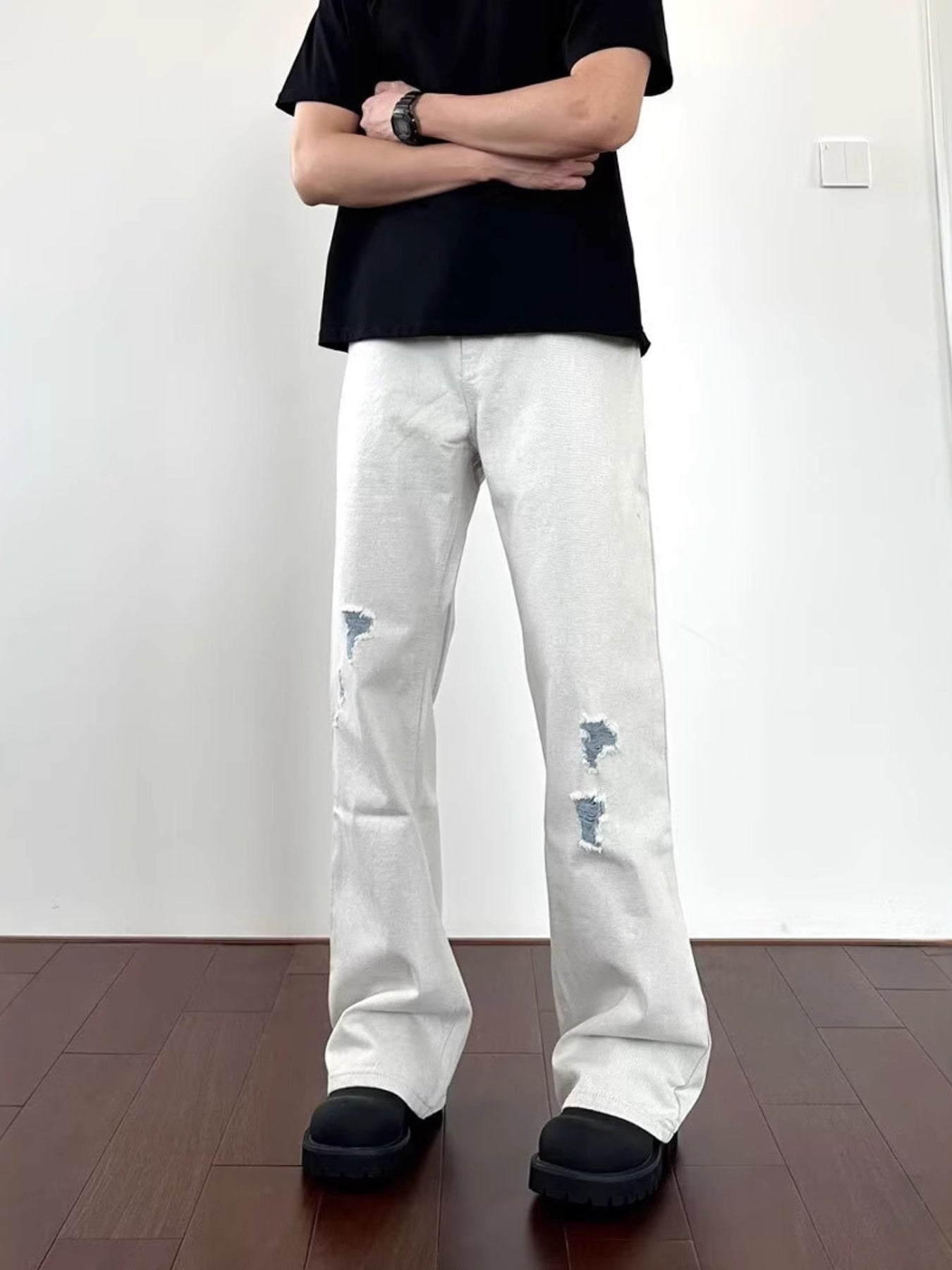 Men's light wash distressed wide-leg jeans with ripped details.