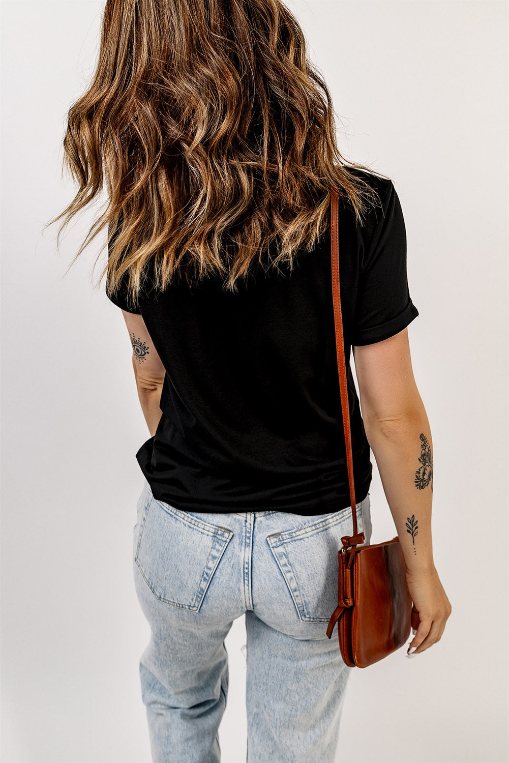 Black t-shirt with rolled sleeves and a crew neck, worn with light wash jeans.