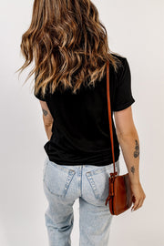 Black t-shirt with rolled sleeves and a crew neck, worn with light wash jeans.