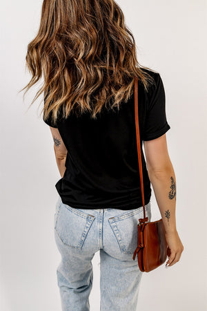 Black t-shirt with rolled sleeves and a crew neck, worn with light wash jeans.