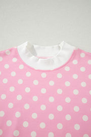 Pink polka dot polyester top with white ribbed mock neck and cuffs.