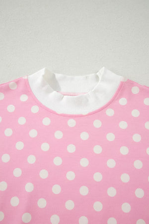 Pink polka dot polyester top with white ribbed mock neck and cuffs.