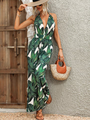 Tropical leaf print halter jumpsuit in dark green with a plunging neckline and wide legs.