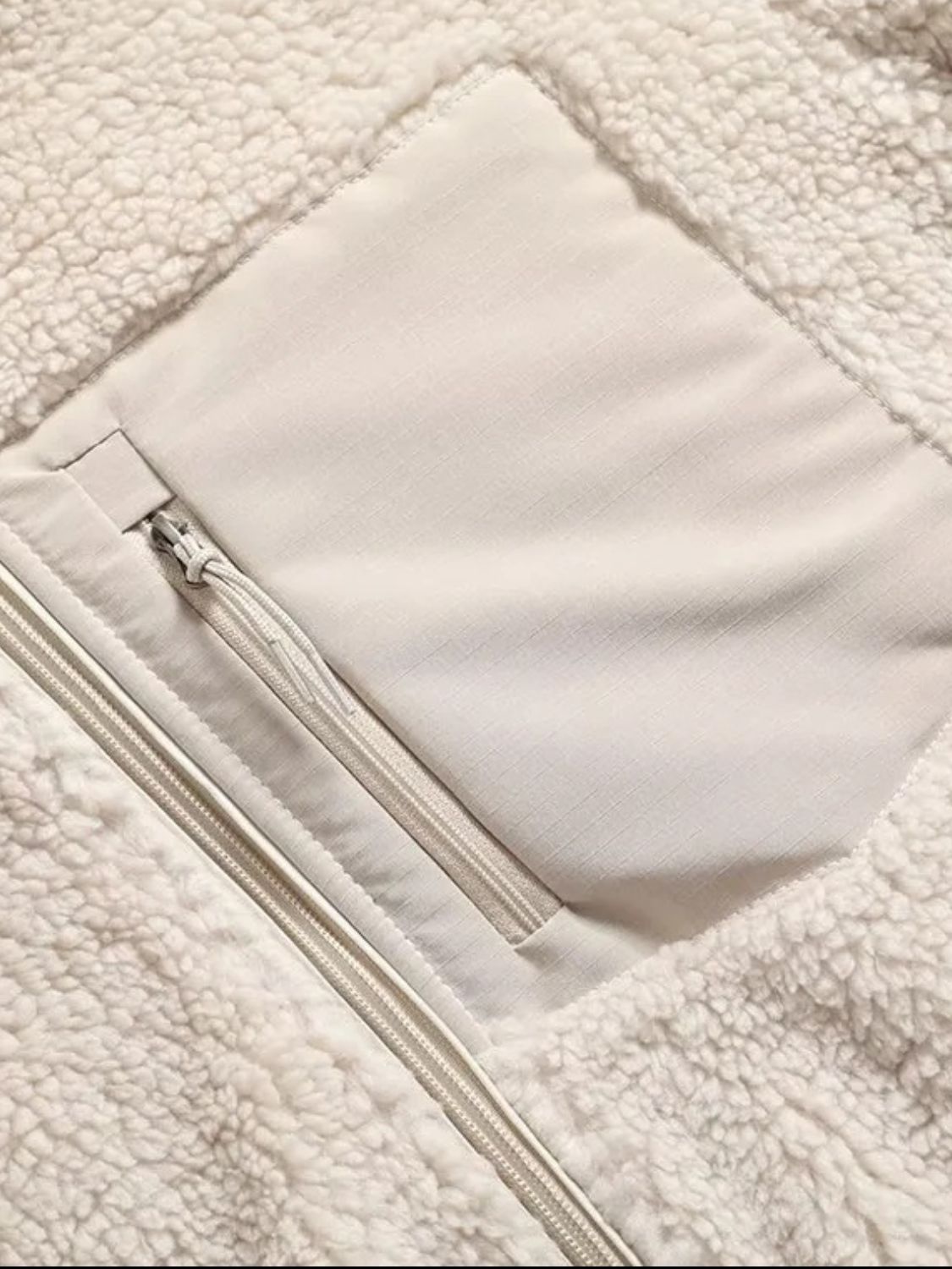 Beige sherpa zip-up jacket with a chest patch pocket and zipper details.