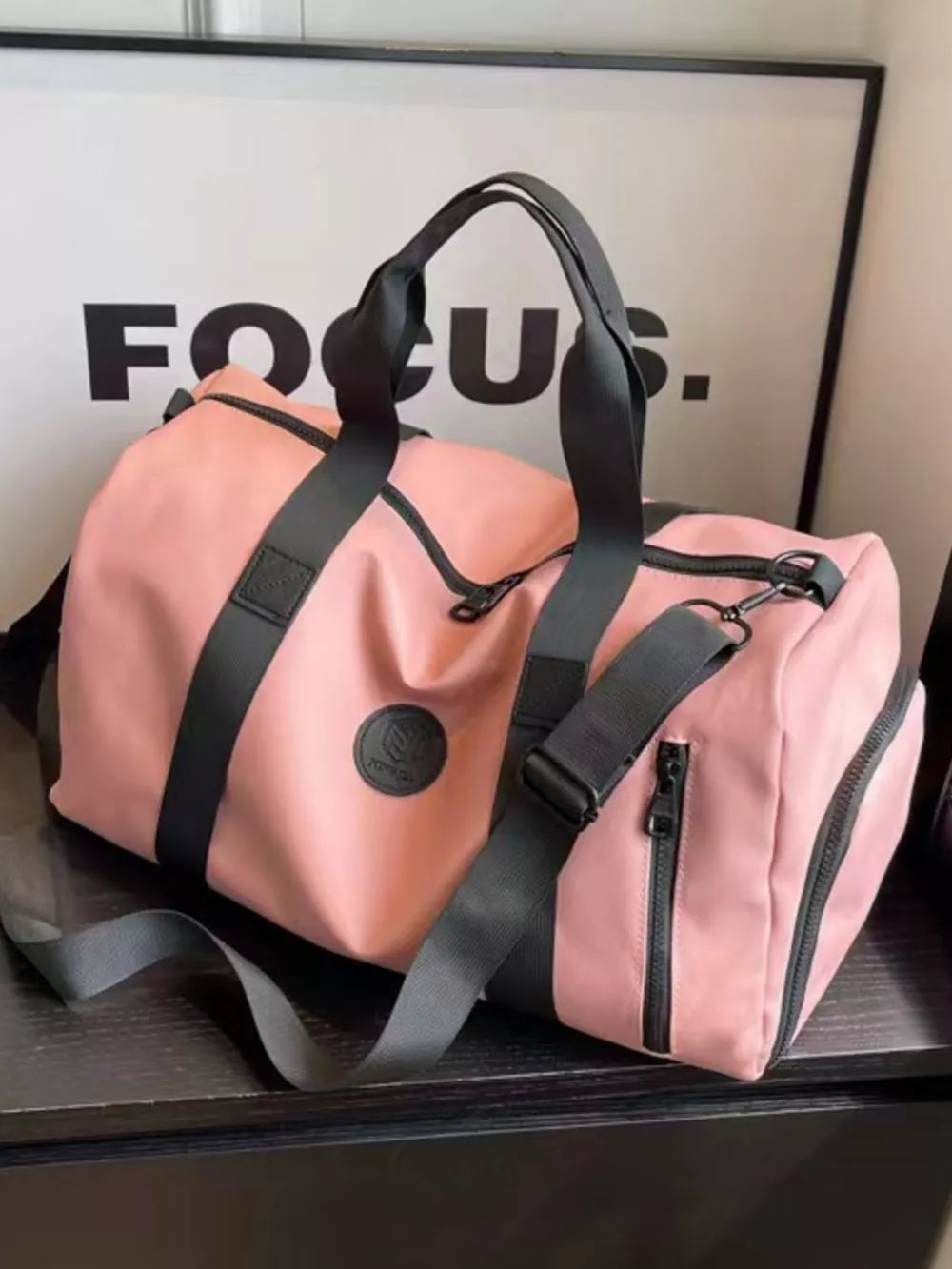 Pink travel organizer bag with black adjustable straps and zippered pockets.