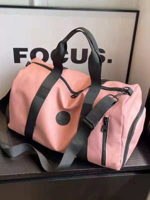 Pink travel organizer bag with black adjustable straps and zippered pockets.
