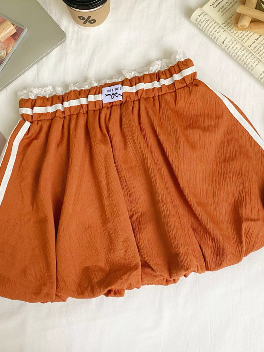 Orange mini skirt with white stripes, lace trim, and gathered waist.