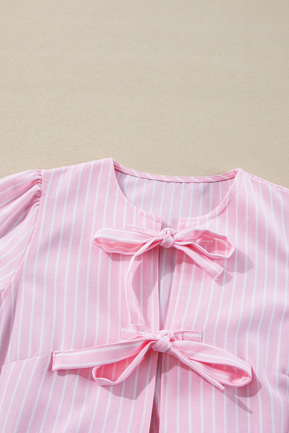 Blush pink striped blouse with bow details and puff sleeves.