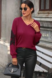 Deep red ribbed knit sweater with black lace appliqué on sleeves, V-neck, long sleeves.