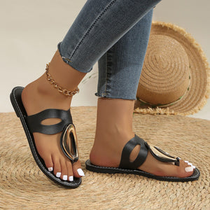 Black open-toe sandals with golden oval accent and contrast stitching.