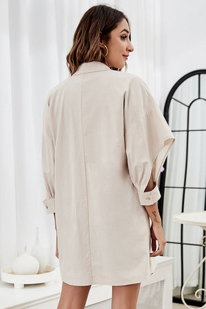 Cream cotton collared shirtdress with open sleeves and tie-front detail.