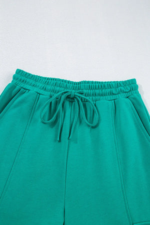 Turquoise lounge pants with elastic waistband, drawstring, and cargo pockets.