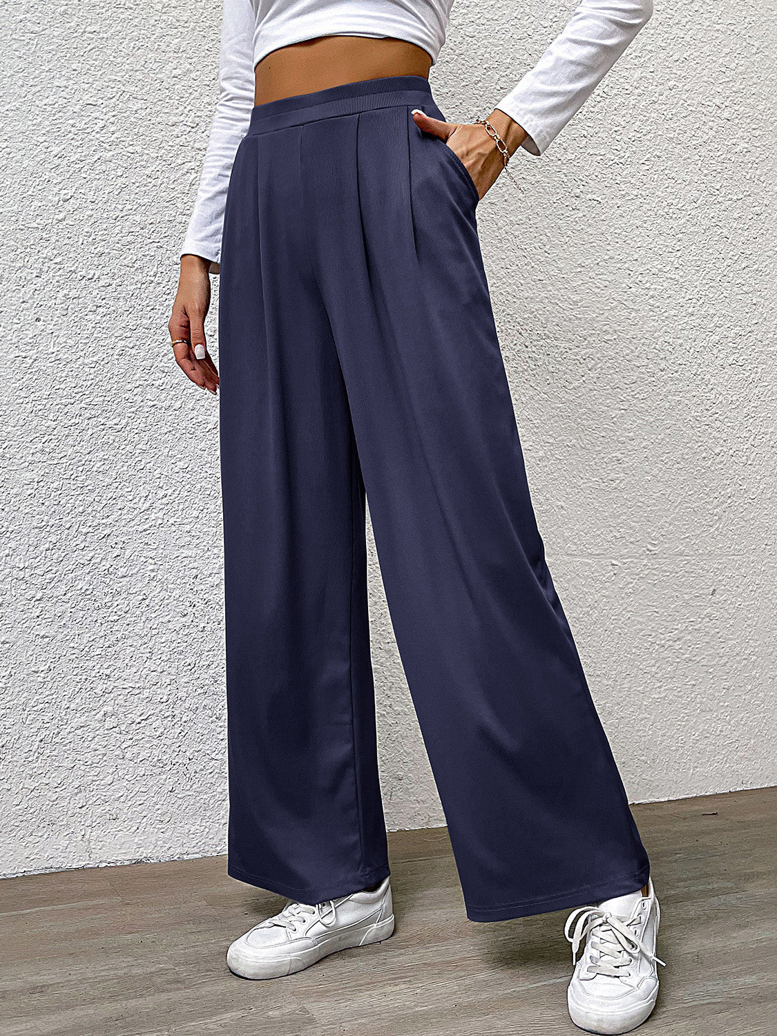 Navy wide leg trousers with front pleats and pockets, styled casually.