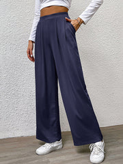 Navy wide leg trousers with front pleats and pockets, styled casually.