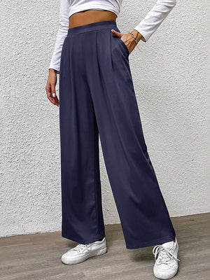 Navy wide leg trousers with front pleats and pockets, styled casually.