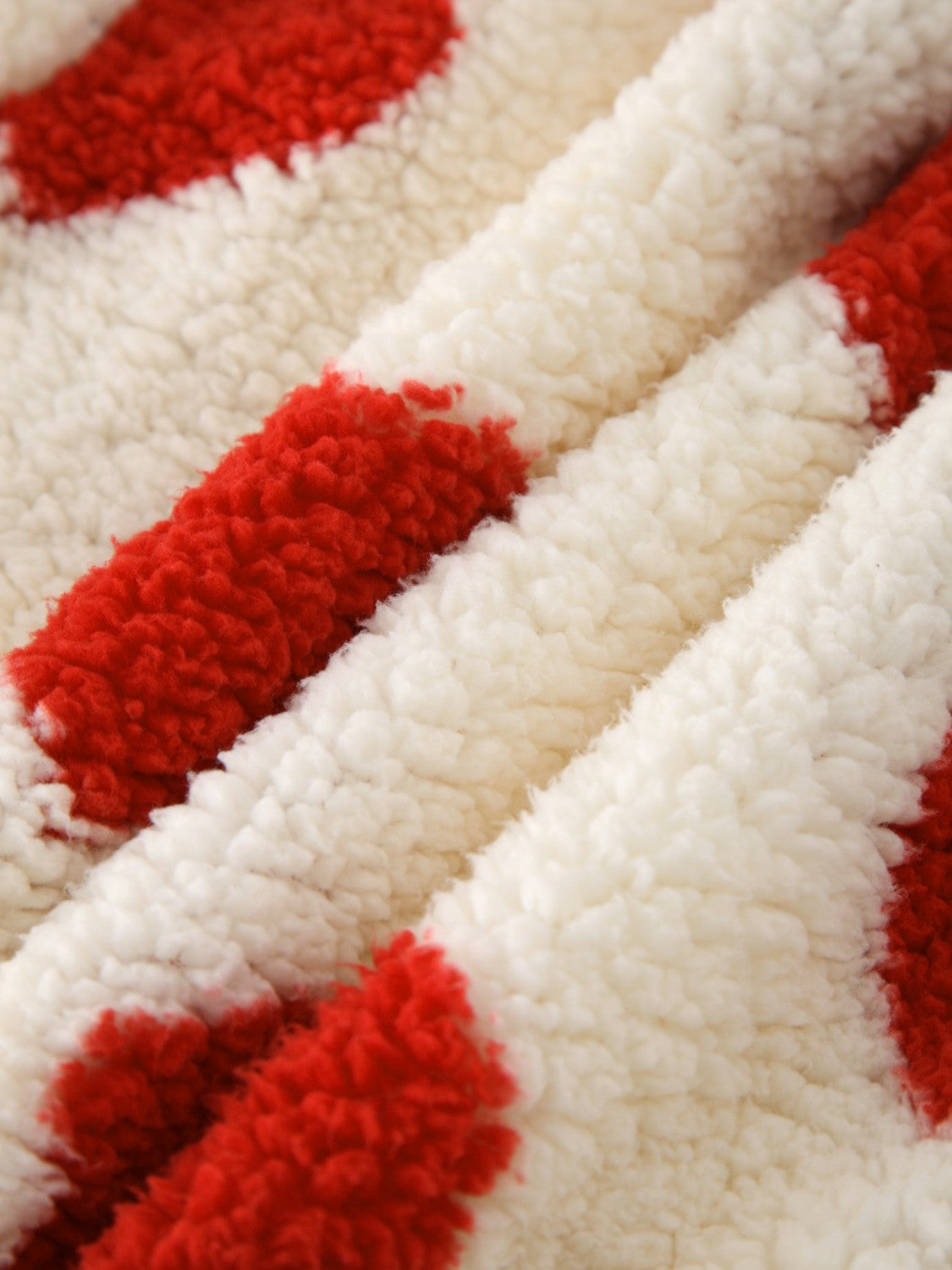Heart print sherpa hoodie in cream with red hearts, showing fuzzy texture.