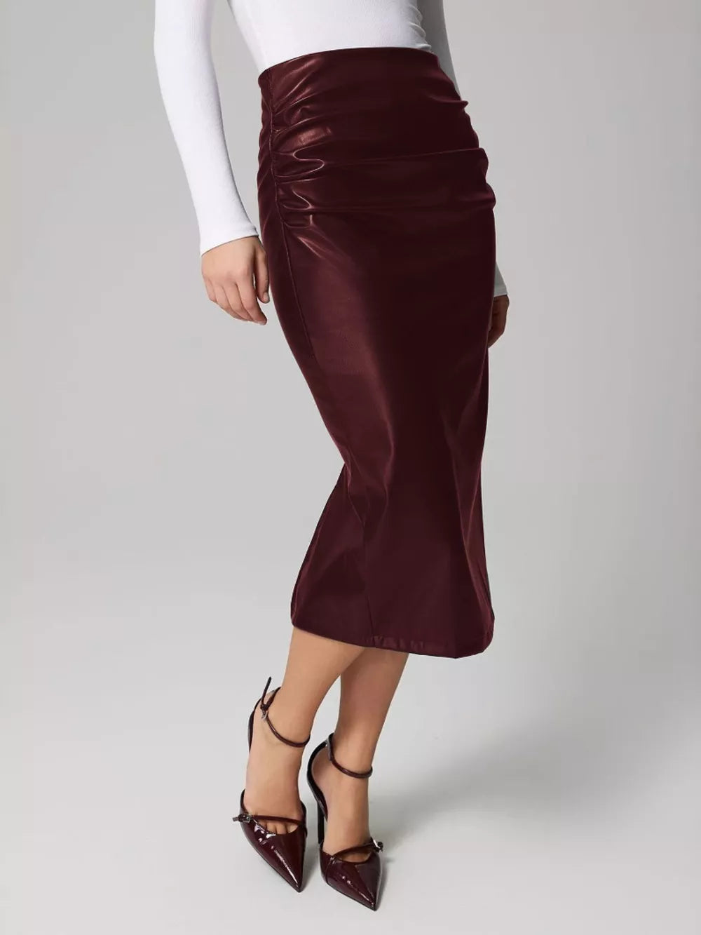 Burgundy faux leather midi skirt with ruched detail and body-con fit.