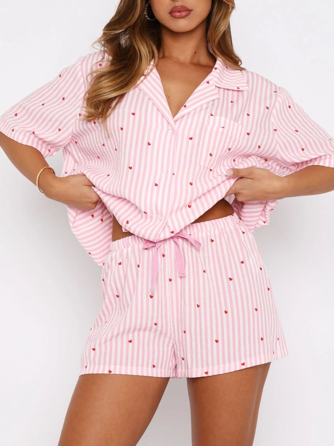 Blush pink striped pajama set with red hearts, collared button-up top and drawstring shorts.