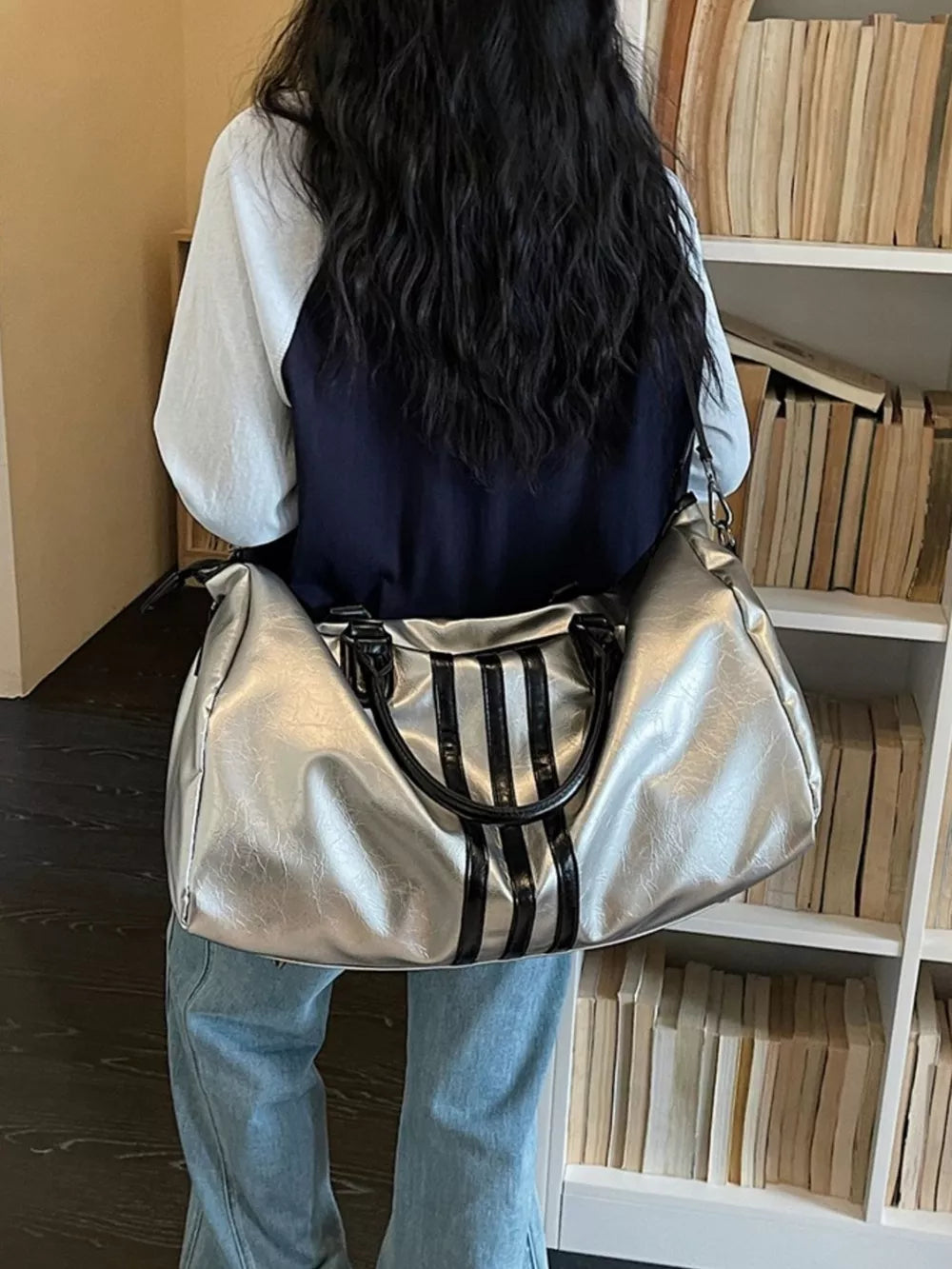 Sleek metallic silver duffle bag with black stripes and black handles.