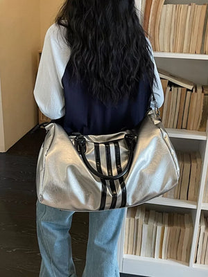 Sleek metallic silver duffle bag with black stripes and black handles.
