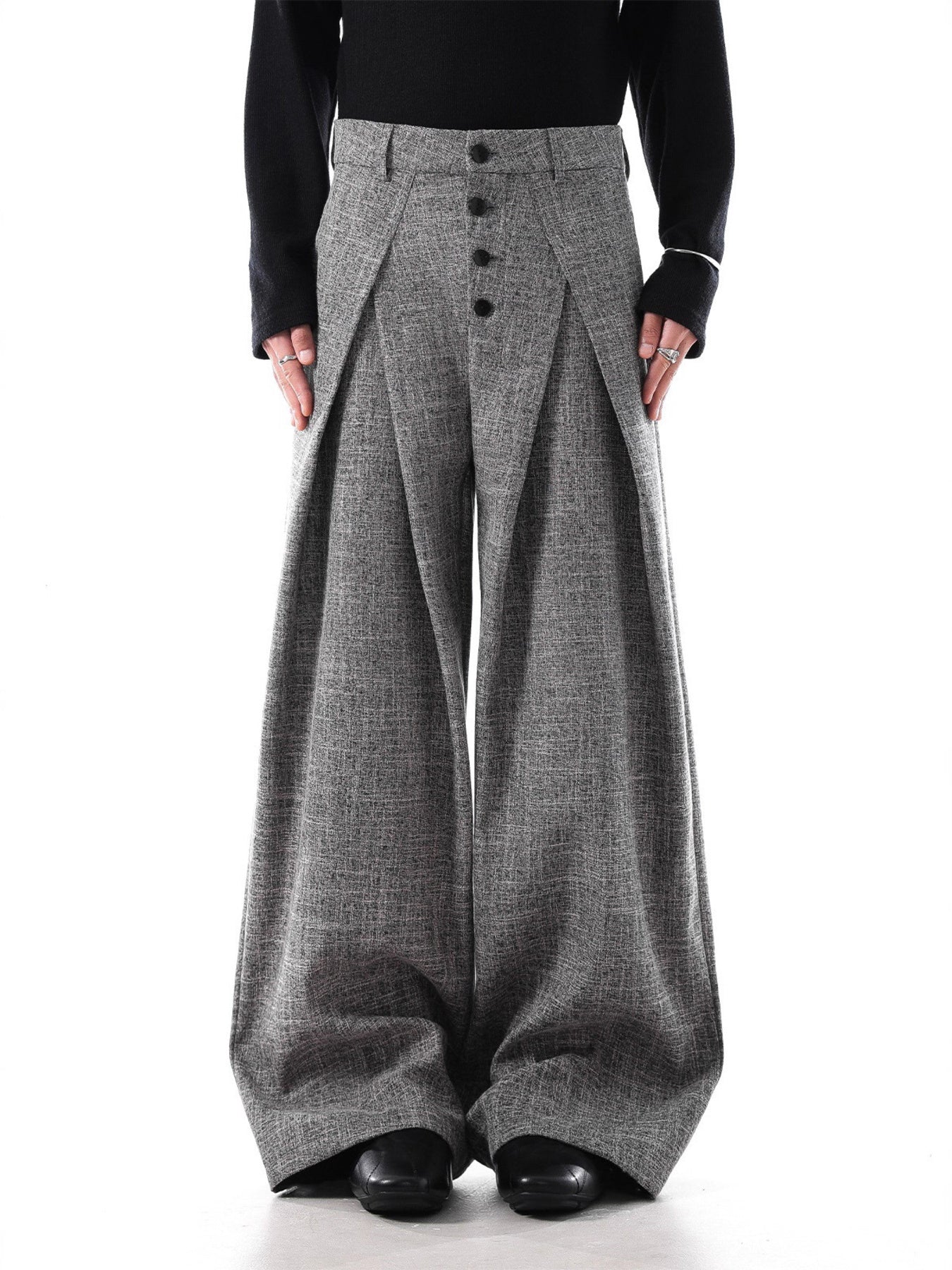 Men's grey oversized pleated wide-leg trousers with button fly and decorative chain detail.