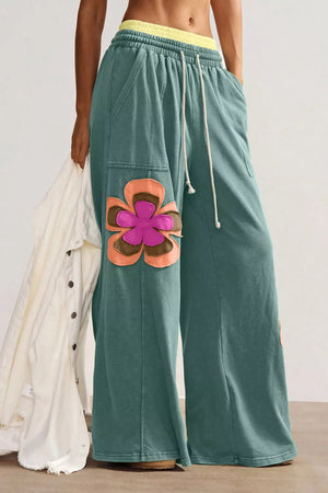 Teal cotton sweatpants with wide legs, drawstring, and colorful floral applique detail.