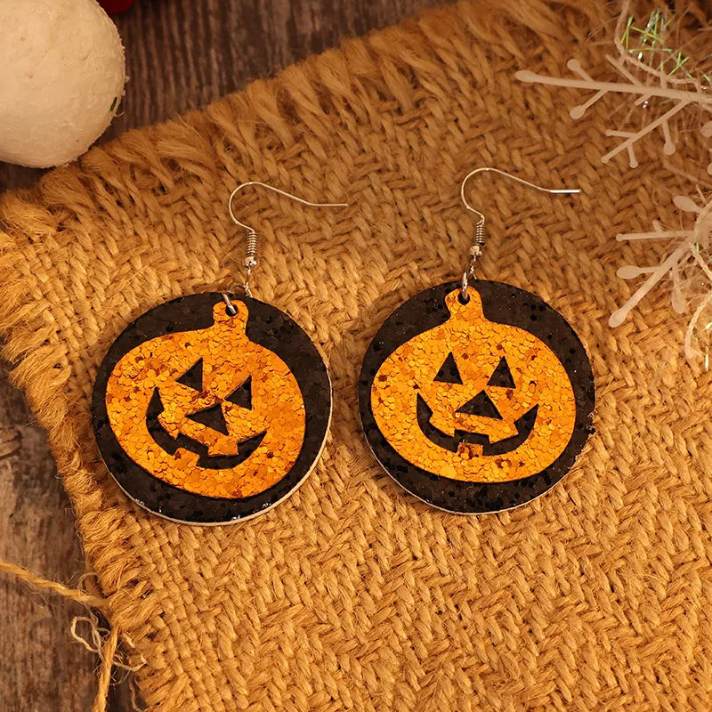 Glitter pumpkin Halloween dangle earrings in tangerine with black accents.