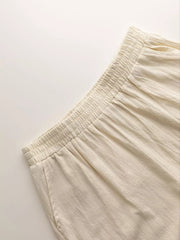 Beige wide-leg pants with elastic waistband and textured fabric detail.