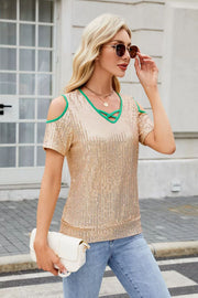 Sequin cold shoulder blouse with crisscross neckline and green trim.