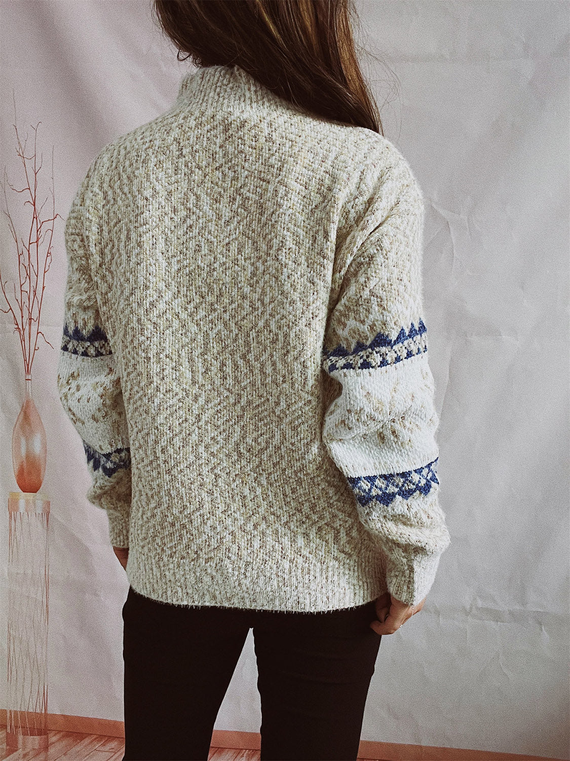 Geometric knit mockneck pullover in neutral tones with blue patterned sleeves.