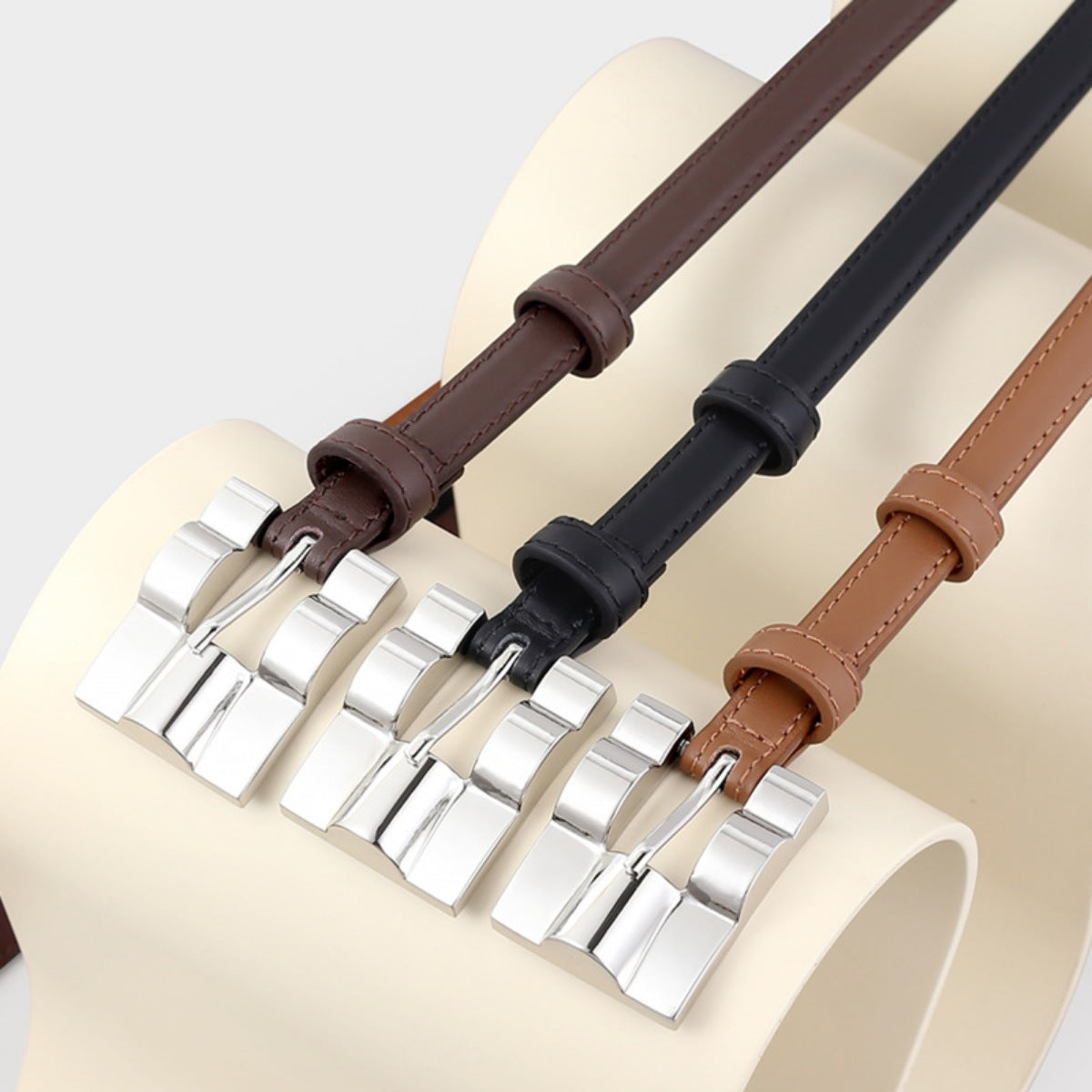 Slim cowhide leather belts in black, coffee brown, and brown with silver buckles.