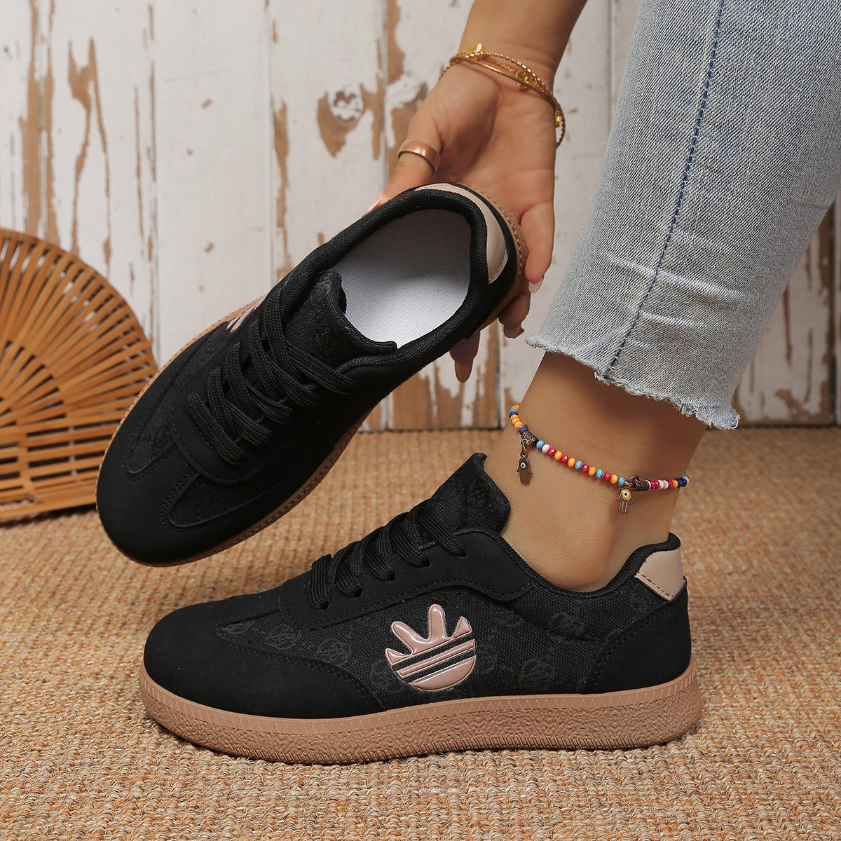 Black round toe lace up sneakers with all over pattern and tan sole.
