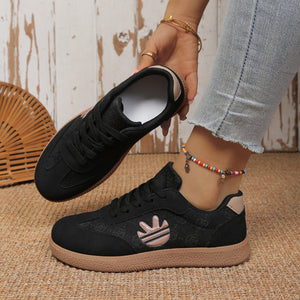 Black round toe lace up sneakers with all over pattern and tan sole.