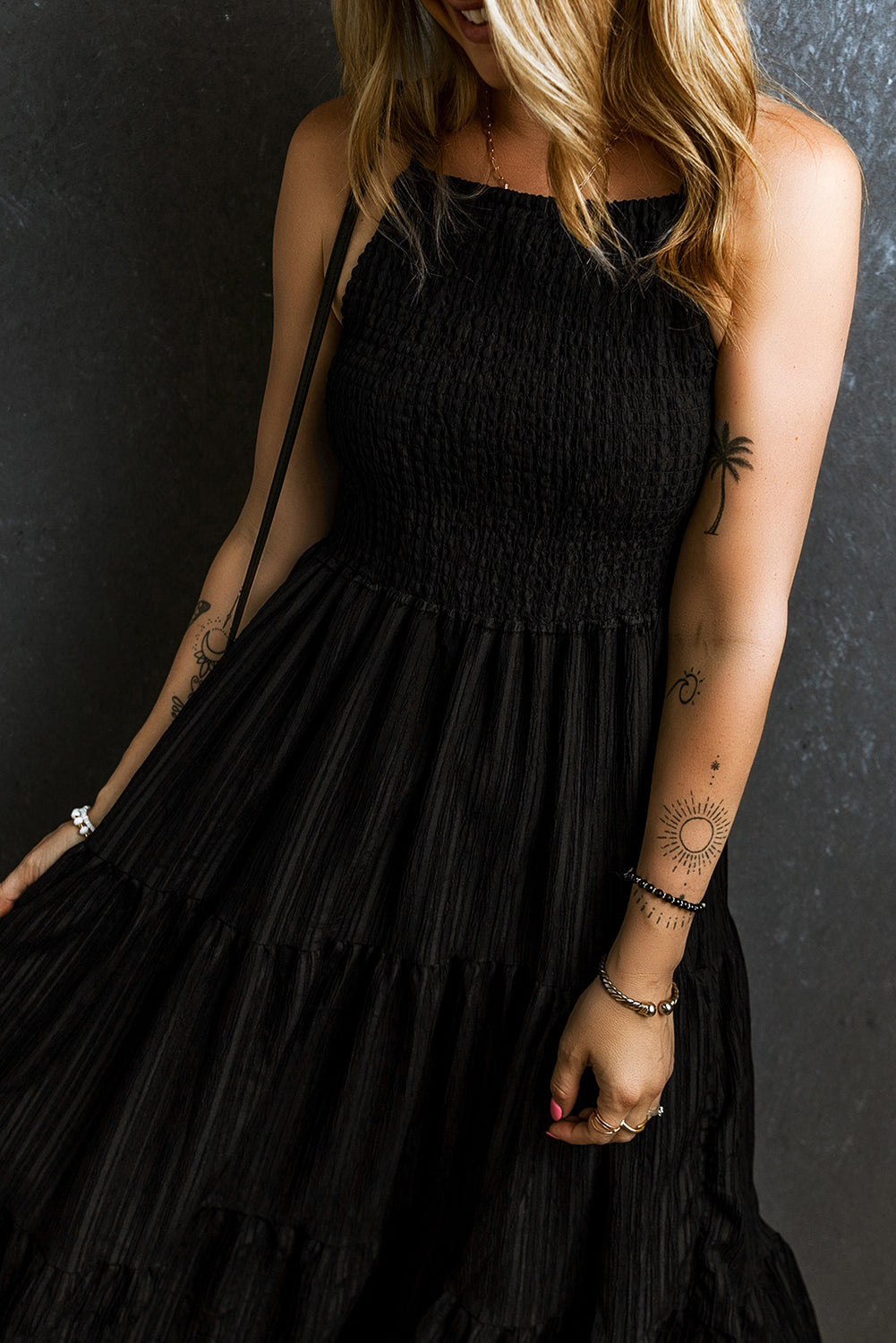 Black tiered maxi dress with textured smocked bodice and thin straps.