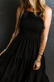 Black tiered maxi dress with textured smocked bodice and thin straps.